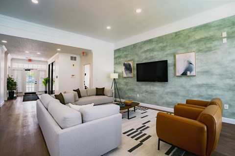 A living room with a white couch and a green wall.