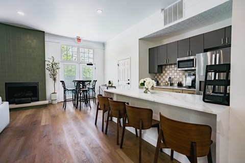 A kitchen with a white counter top and wooden chairs.