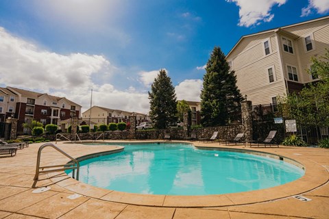 A swimming pool surrounded by a stone wall and trees.