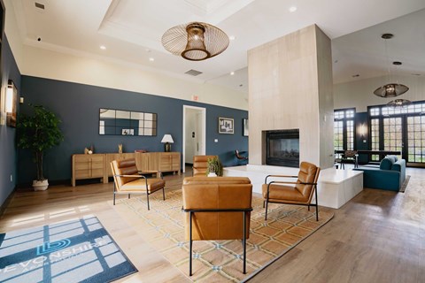 A living room with a blue rug and brown chairs.