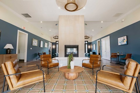 A living room with a fireplace and brown leather chairs.