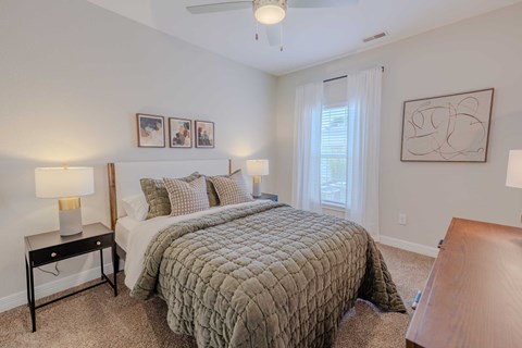 A bedroom with a bed, nightstand, and pictures on the wall.