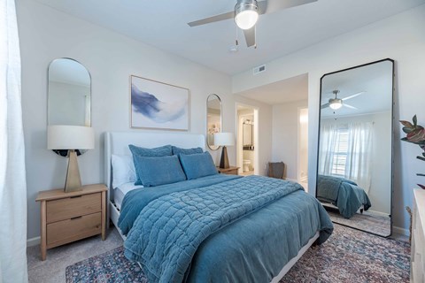 A bedroom with a large bed and a ceiling fan.