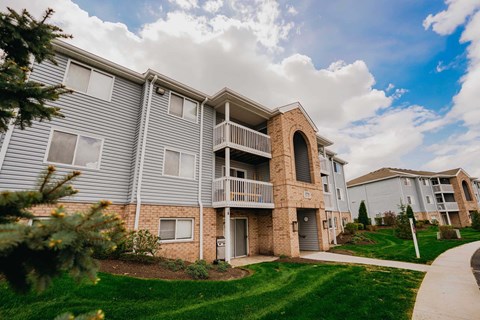 A residential building with a balcony and a small garden in front.