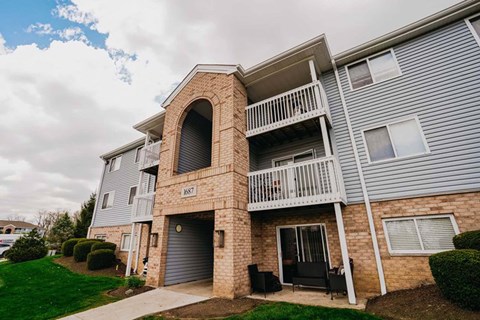 A two-story apartment building with a balcony and a garage door.