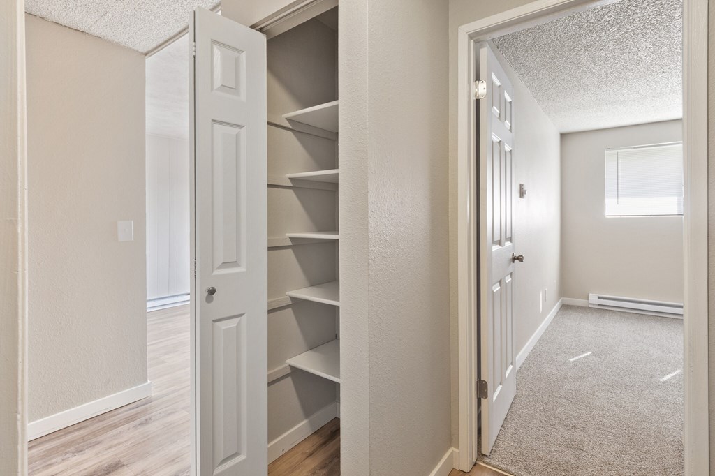 A white door is open to a hallway with a carpeted floor.