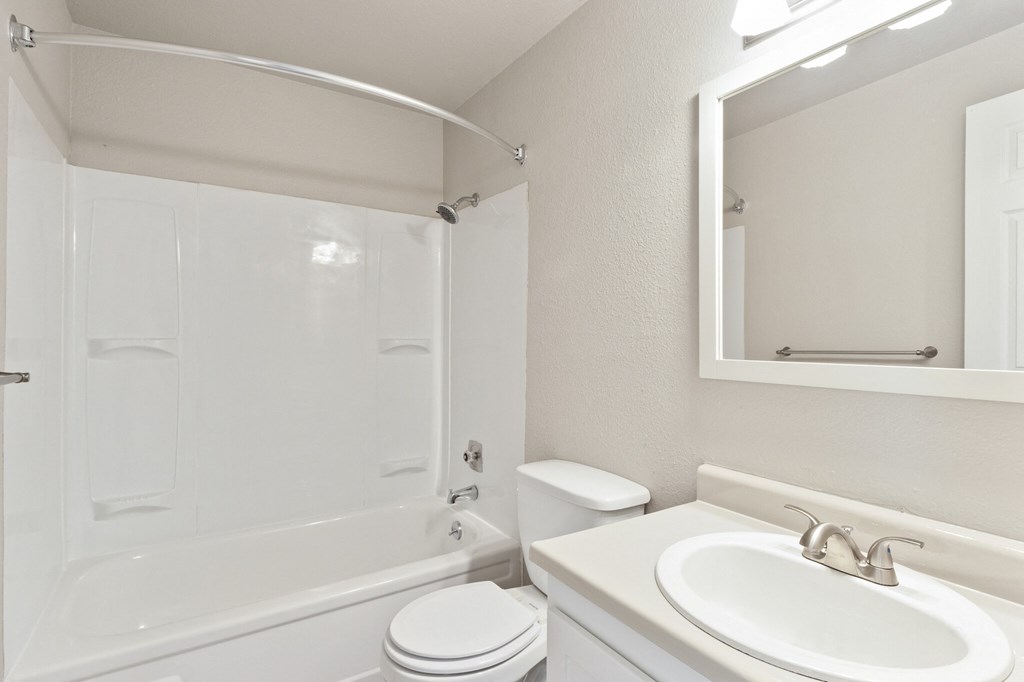 A white bathroom with a toilet, sink, and bathtub.
