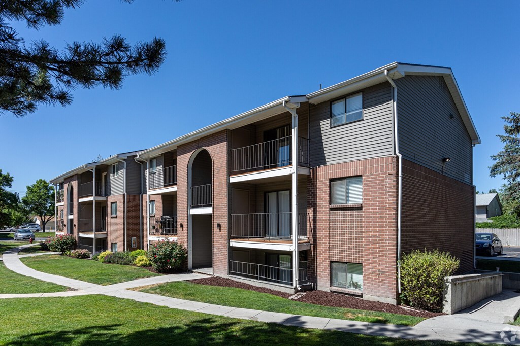 A multi-story apartment building with balconies and a clear blue sky above.