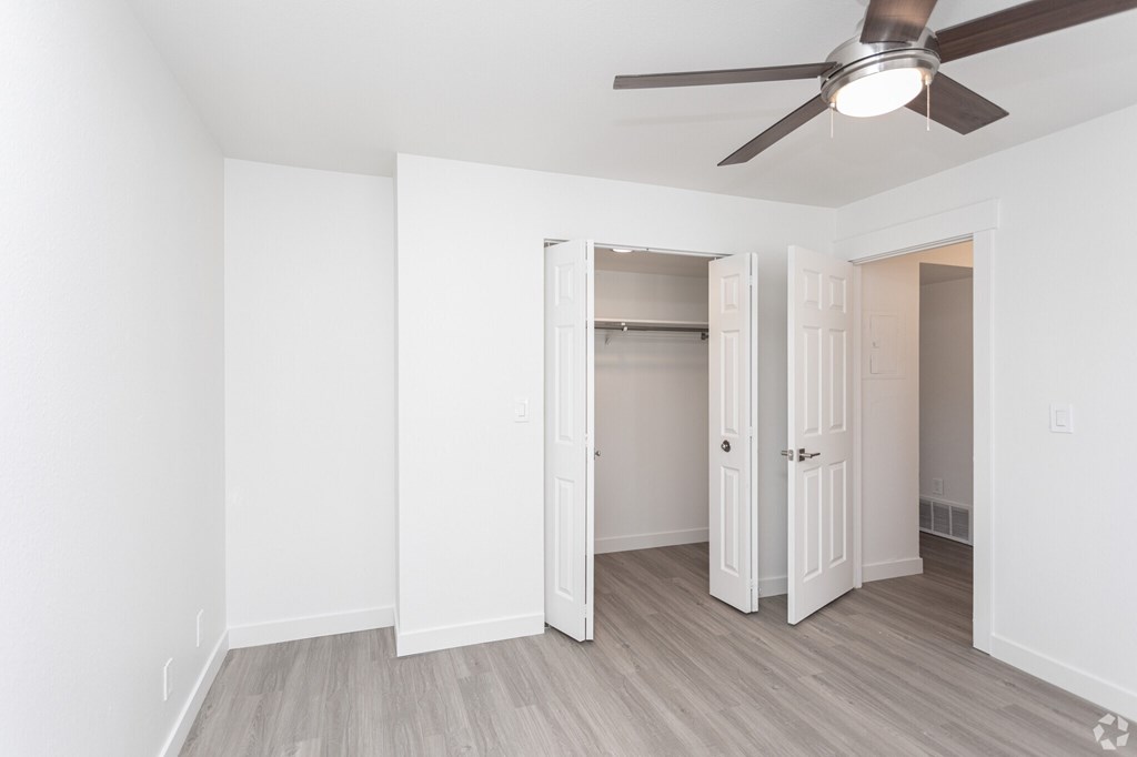 A room with a ceiling fan and a doorway leading to another room.
