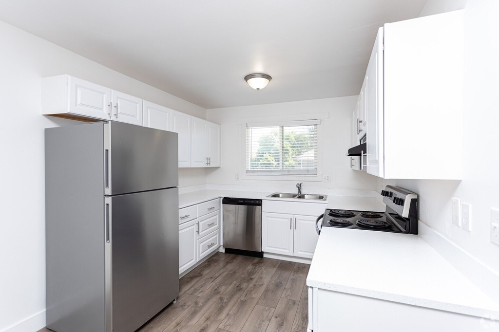 A modern kitchen with a stainless steel refrigerator and white cabinets.