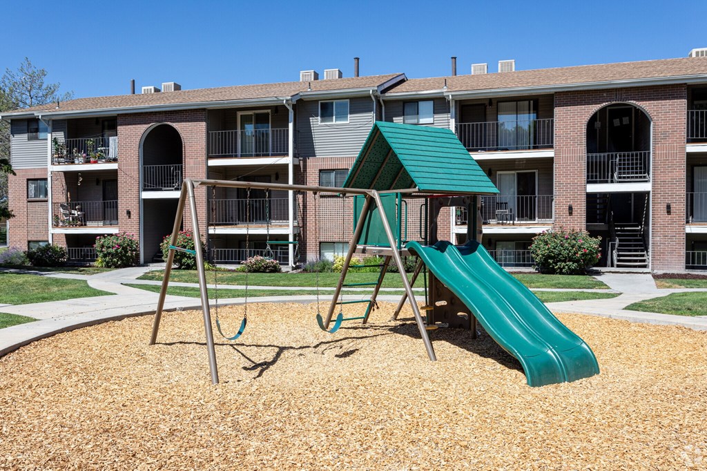 A playground with a green slide and a green roofed structure.