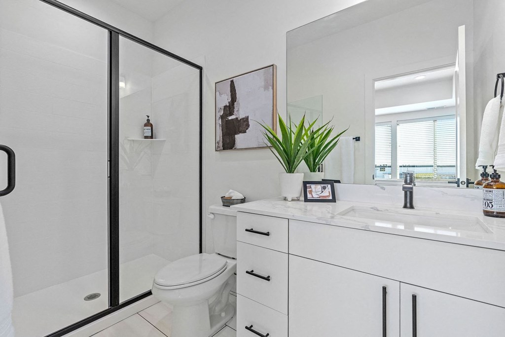 a white bathroom with a shower, a toilet, and a sink