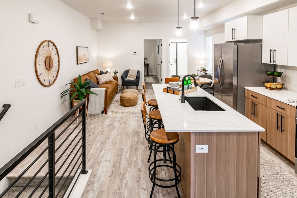 a kitchen and living room with a white counter top and a stainless steel refrigerator