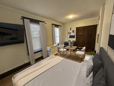 A bedroom with a large bed and a small kitchenette.