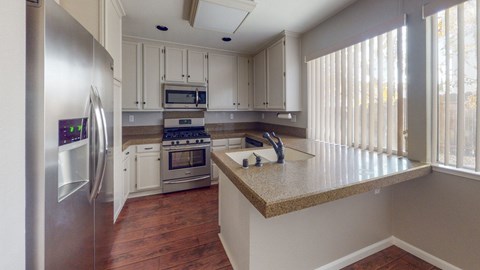 A kitchen with a refrigerator, oven, and microwave.