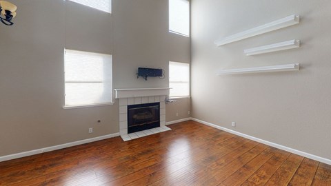 A living room with a fireplace and wooden floors.