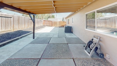 A concrete patio with a grey tile border and a concrete walkway.