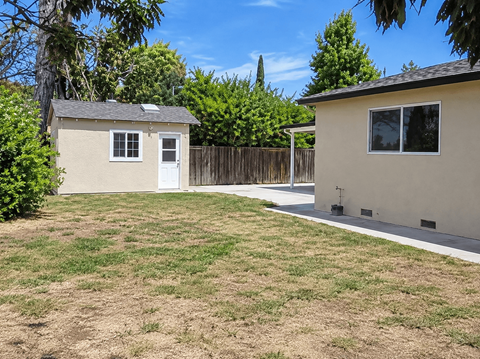 A backyard with a shed and a house.
