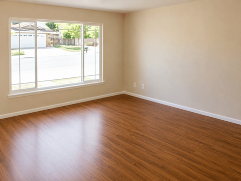 A room with wooden flooring and a large window.