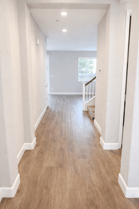 A long hallway with wood floors and white walls.