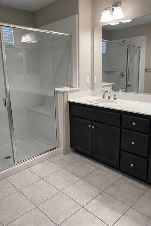 A bathroom with a sink, mirror, and shower.