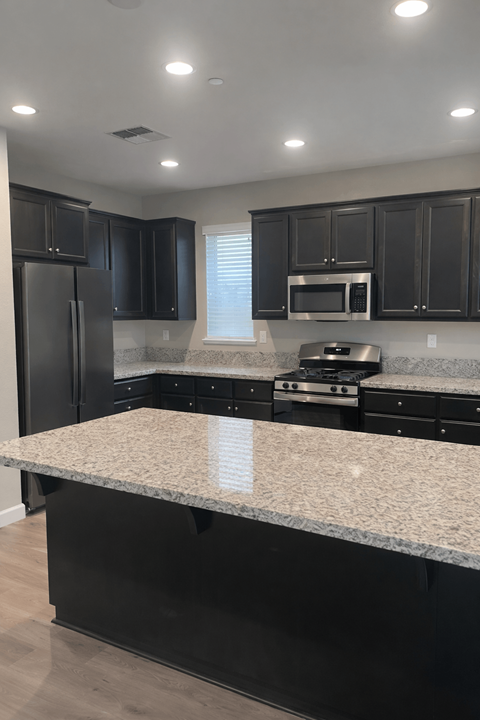 A kitchen with black cabinets and a granite countertop.