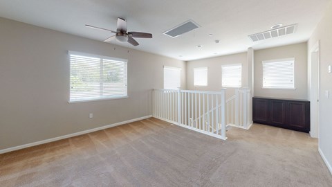 A spacious room with a fan, carpeted floor, and a window with blinds.