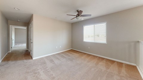 A room with a ceiling fan and a window with blinds.