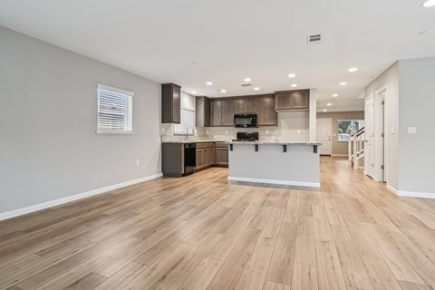 A kitchen with wooden floors and a white wall.