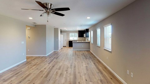 A spacious room with wooden flooring and a ceiling fan.