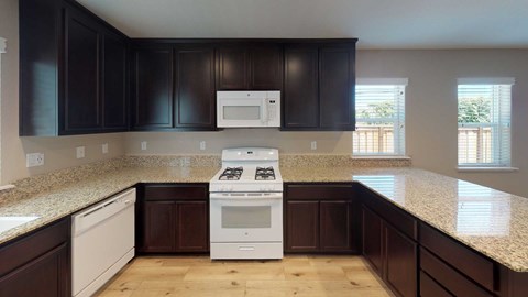 A kitchen with dark brown cabinets and a white stove top oven.