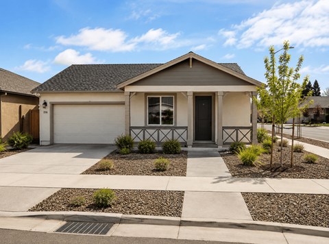 A house with a white garage door and a small front yard with a tree.