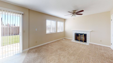 A living room with a fireplace and a ceiling fan.