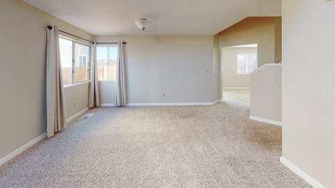A spacious room with carpeted floor and sliding glass doors.