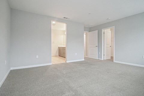 A large empty room with carpeted floor and white walls.