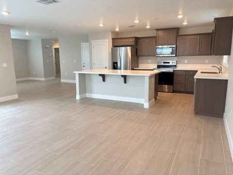A kitchen with a white island and wooden flooring.