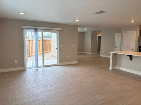A spacious room with a sliding glass door leading to a backyard.