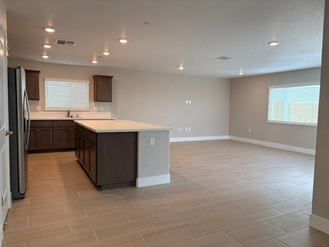 A kitchen with a refrigerator on the left and a countertop with a sink.