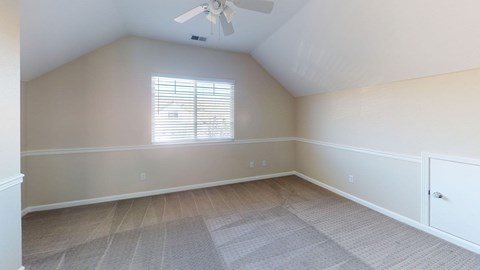 A room with a ceiling fan and a window with blinds.