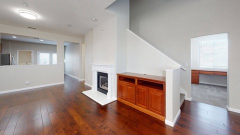 A living room with a fireplace and wooden floors.