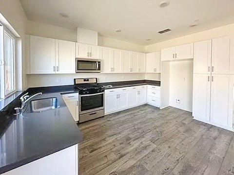A kitchen with white cabinets and a black countertop.