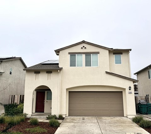 A two-story house with a red door and a garage door.