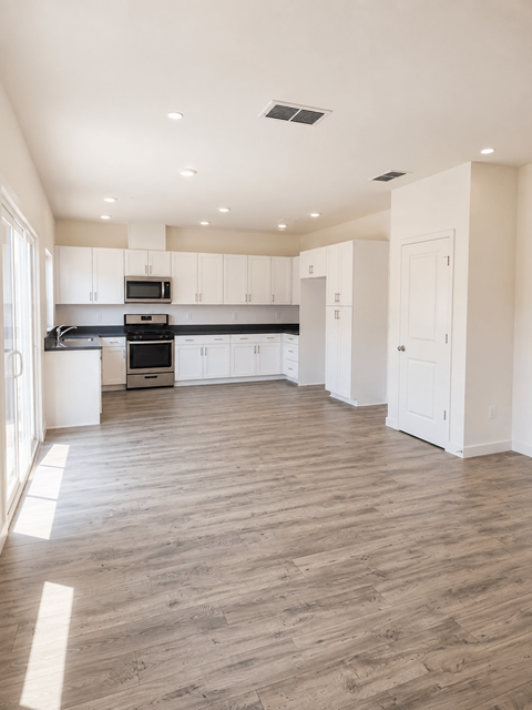 A kitchen with white cabinets and a wooden floor.