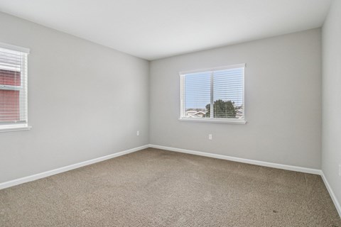 A room with a carpeted floor and a window with blinds.