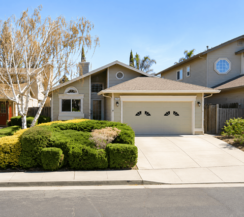 A house with a garage and a tree in front.