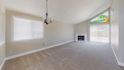 A room with a carpeted floor, a fireplace, and a chandelier.