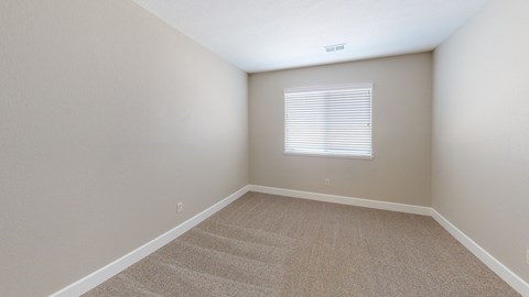 A room with a carpeted floor and a window with blinds.