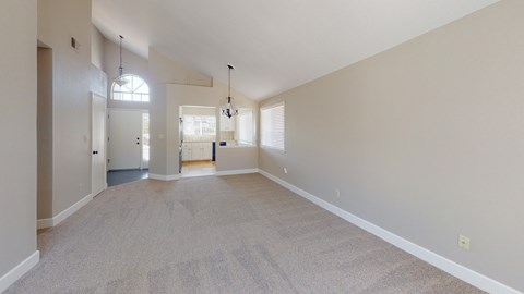A spacious room with a carpeted floor and white walls.