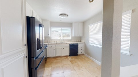 A kitchen with a black fridge and white cabinets.