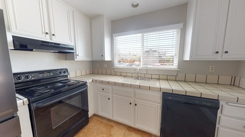 A kitchen with white cabinets and black appliances.